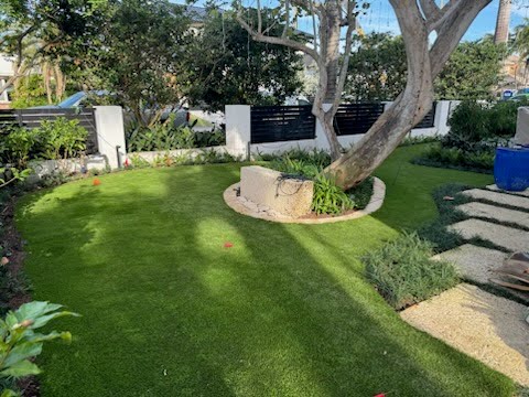 An example of one of the many artificial grass front yard ideas, featuring a combination of turf with stone walkways and lush garden beds. The image highlights a perfect balance of natural elements and modern design, creating a welcoming entryway.