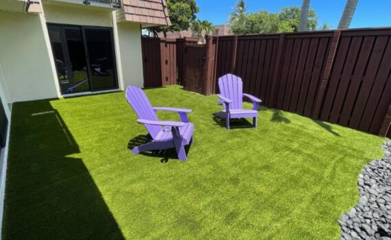 Person brushing artificial turf and applying baking soda to remove dog urine odor.